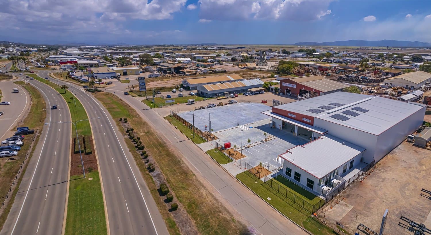 Aerial view of a commercial building and car park beside a highway